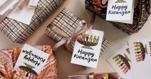 Several wrapped gifts are laid on a table with cards that say Happy Kwanzaa